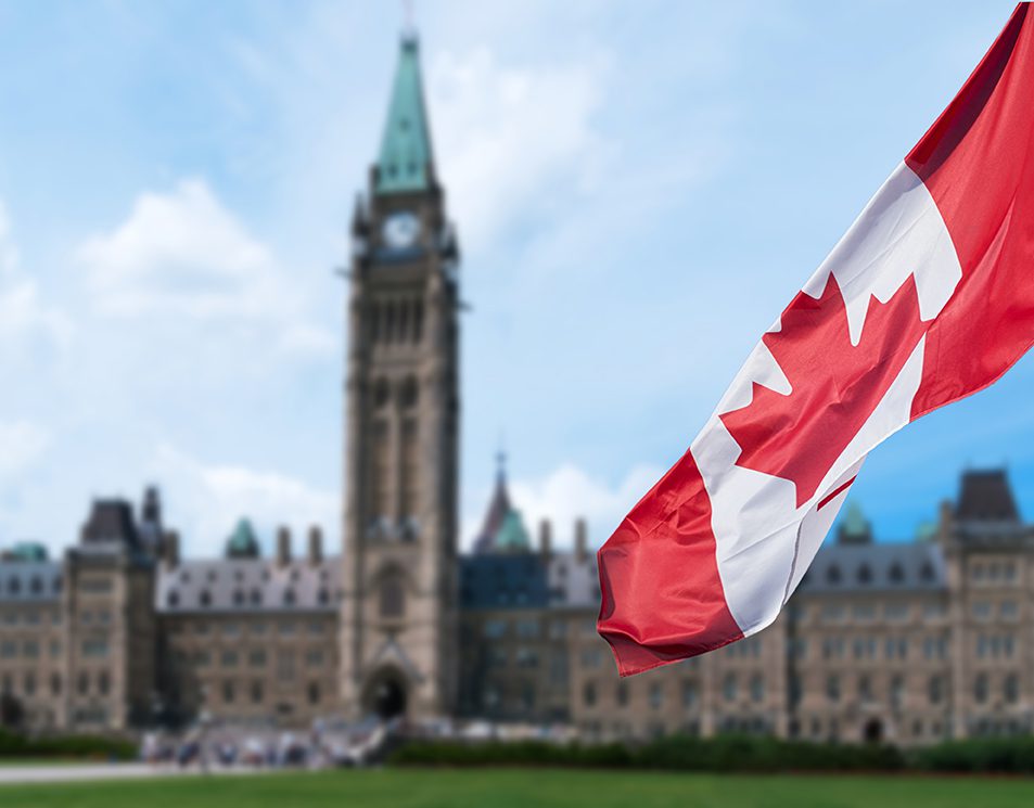 Drapeau du Canada flottant devant le Parlement, symbolisant des opportunités pour travailler au Canada.